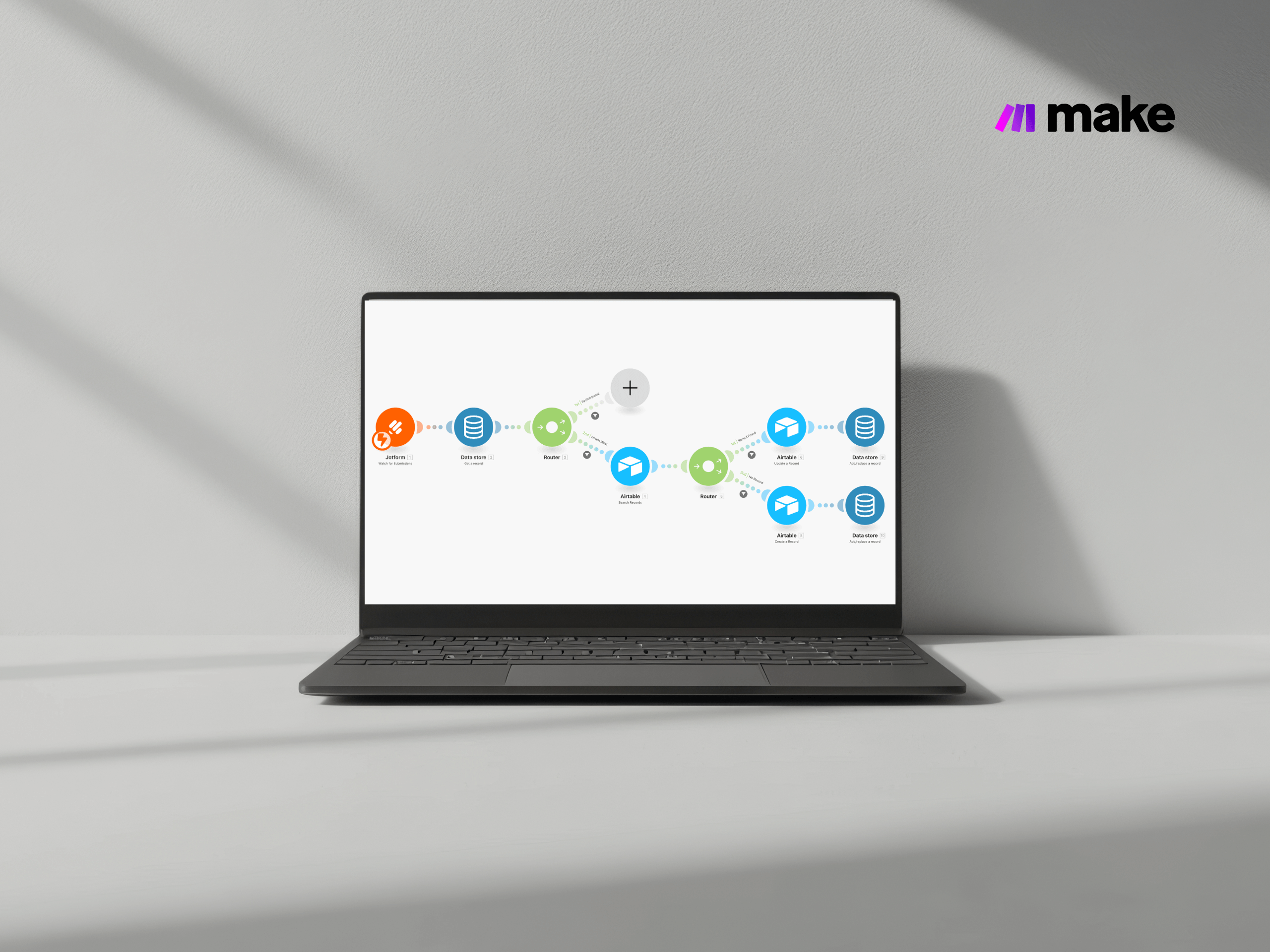 Ein Laptop auf einer weißen Fläche zeigt auf seinem Bildschirm ein Flussdiagramm mit verbundenen bunten Symbolen. In der rechten oberen Ecke ist das Make-Logo zu sehen, das den innovativen Geist einer führenden Digitalagentur München vor einer hellgrauen Wand widerspiegelt. - NINE brackets Digitalagentur München